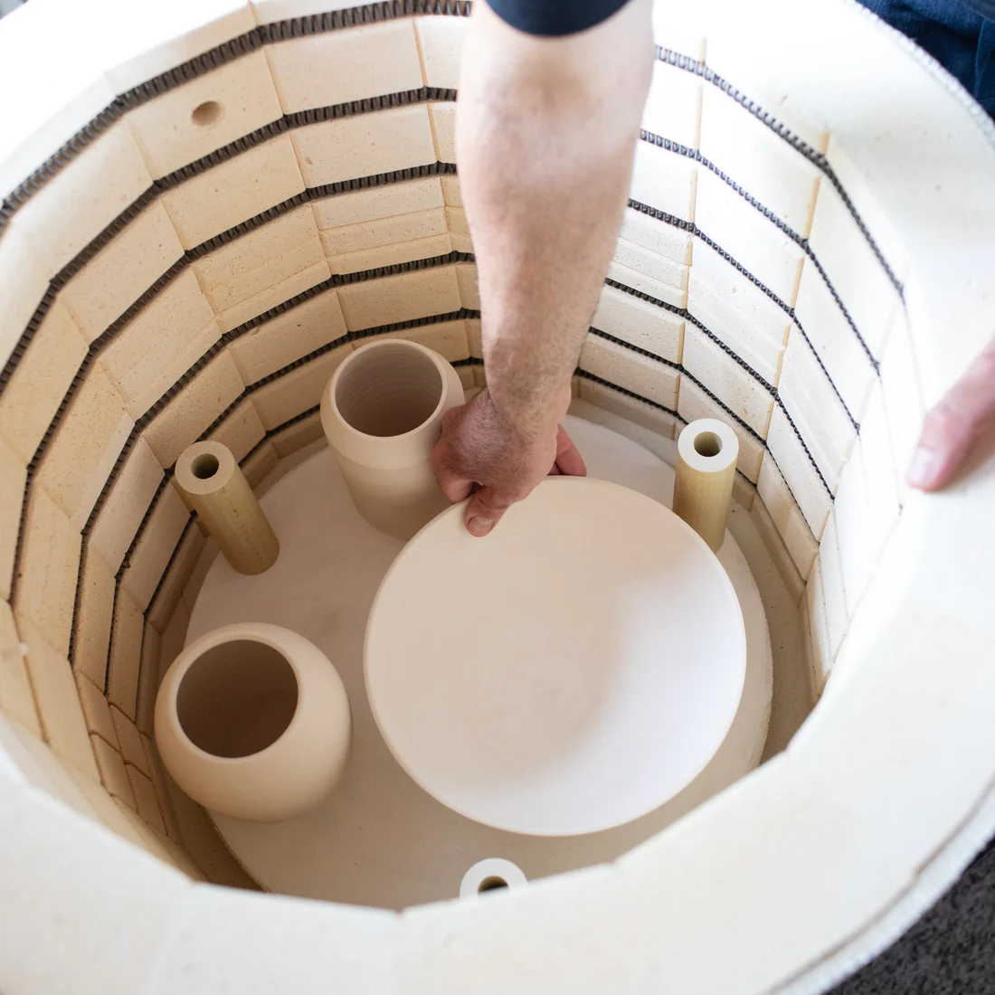 Bestücken des Brennofens mit ungebrannten Keramikstücken im Atelier Inochiceramic