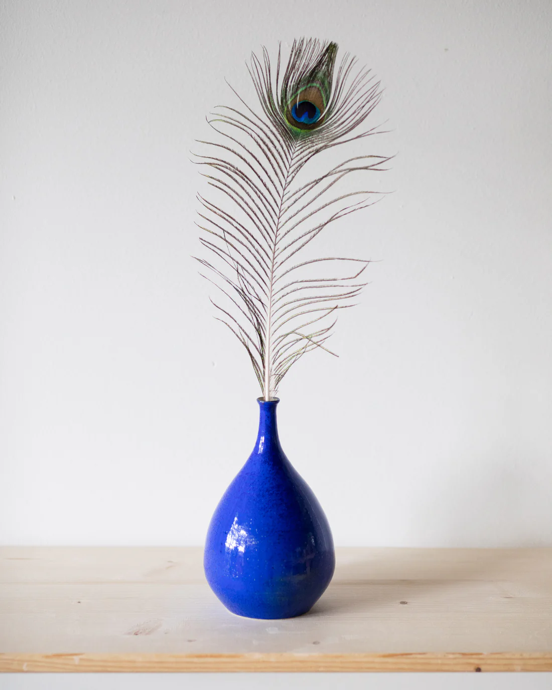 Kobaltblaue Flaschenvase mit Pfauenfeder — handgemachte Keramik aus dem Atelier im Aargau
