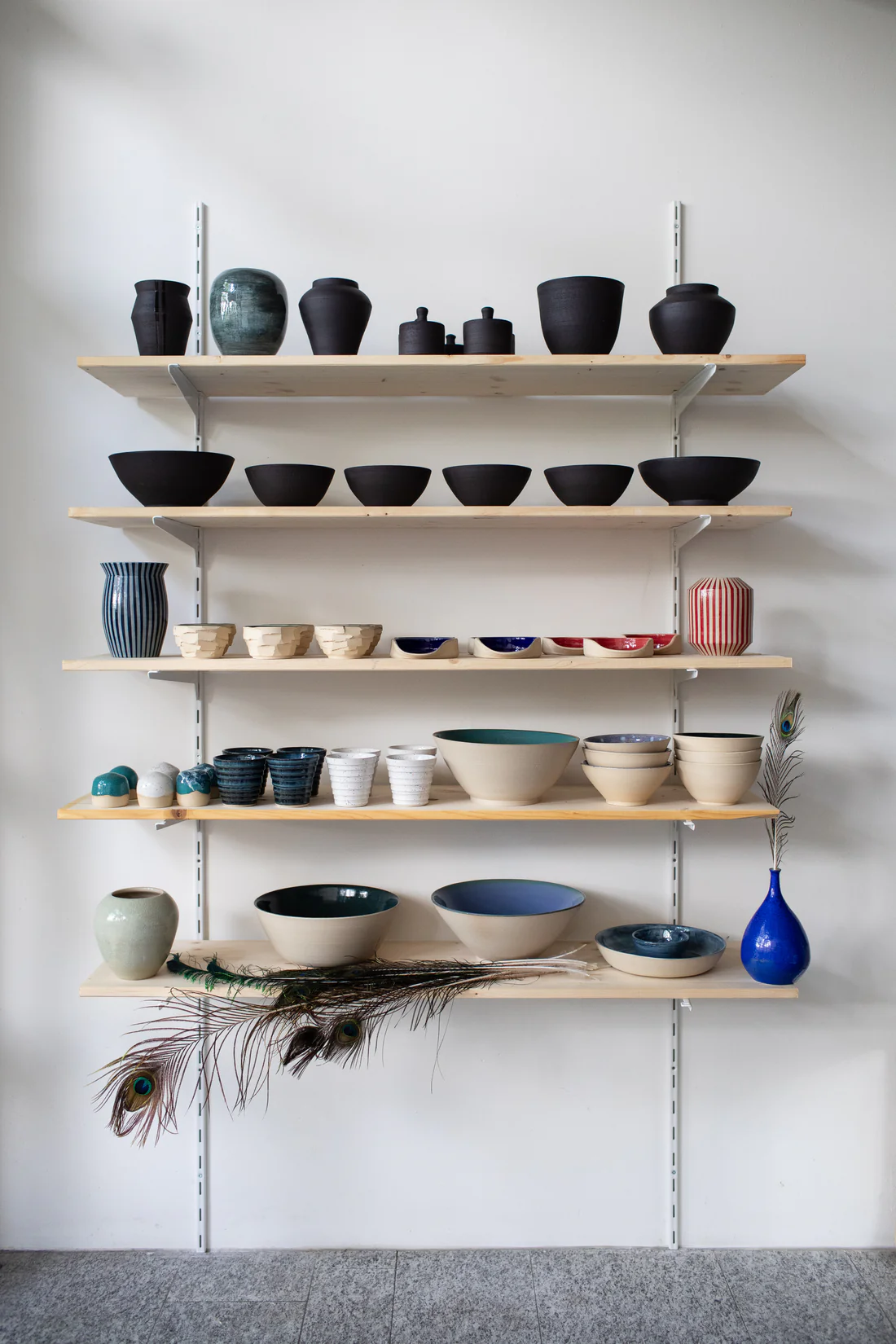 Wandregal im Atelier mit einer Auswahl handgemachter Keramik von Inochiceramic — Vasen, Schalen, Becher