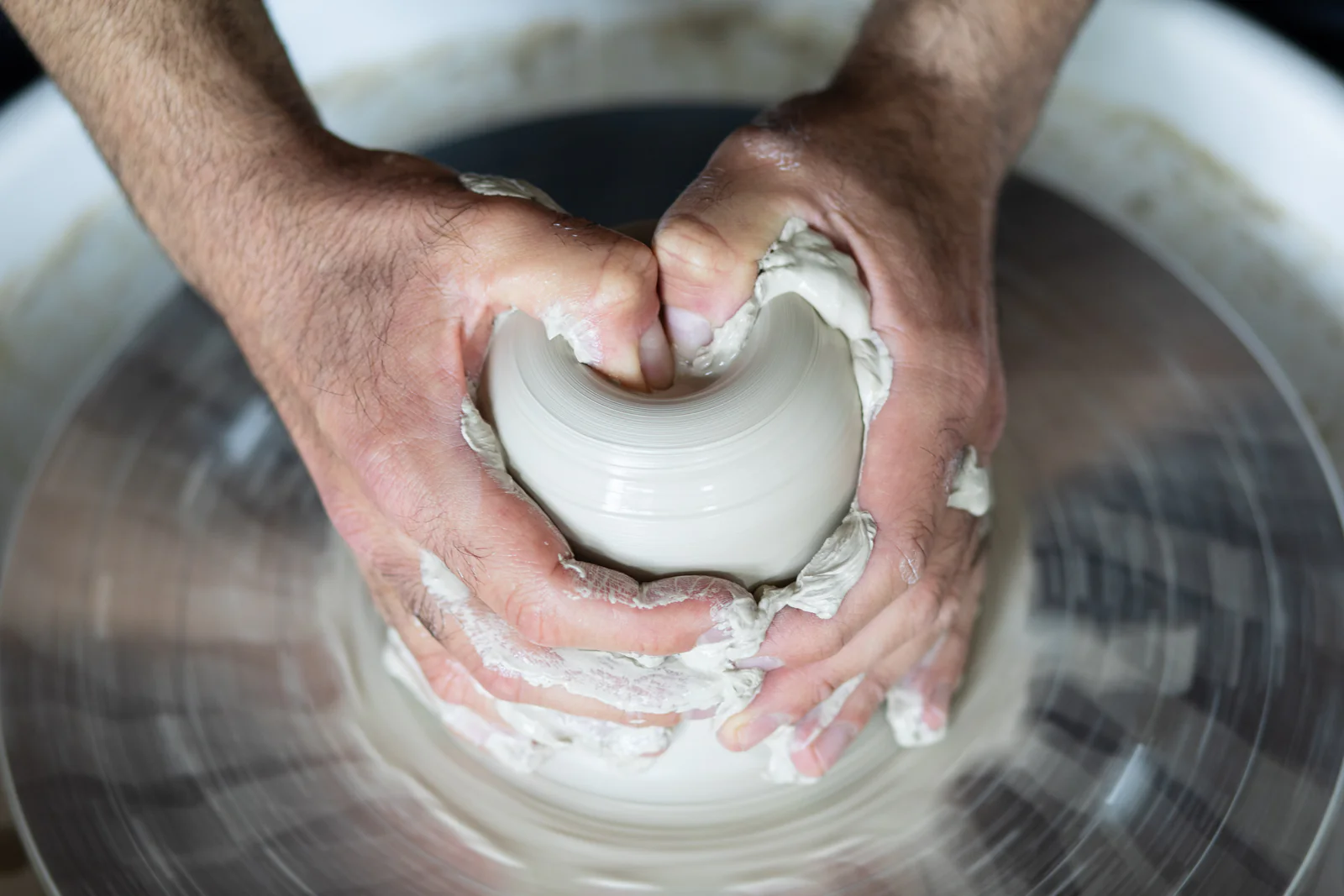 Hände formen frischen Ton an der Töpferscheibe — handgemachte Keramik aus dem Atelier Inochiceramic
