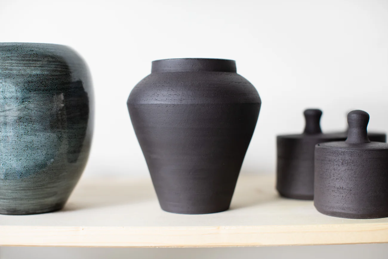 Petrolfarbene Vase, schwarze Steinzeug-Vase und zwei Deckeldosen auf einem Holzregal — handgemachte Keramik von Inochiceramic